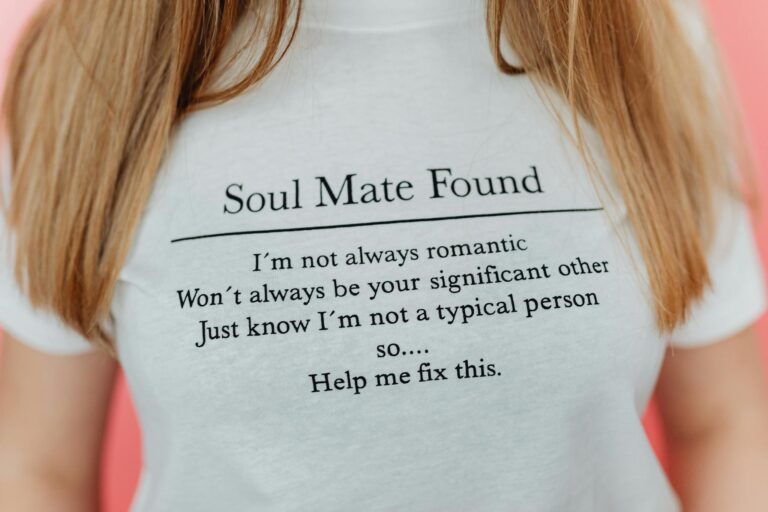 Close-up of a white t-shirt with a witty soul mate message on a pink background.